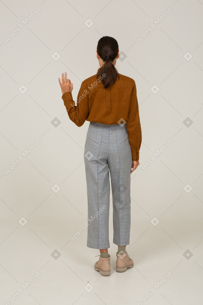 Vue arrière d'une jeune femme asiatique en culotte et chemisier montrant un geste ok