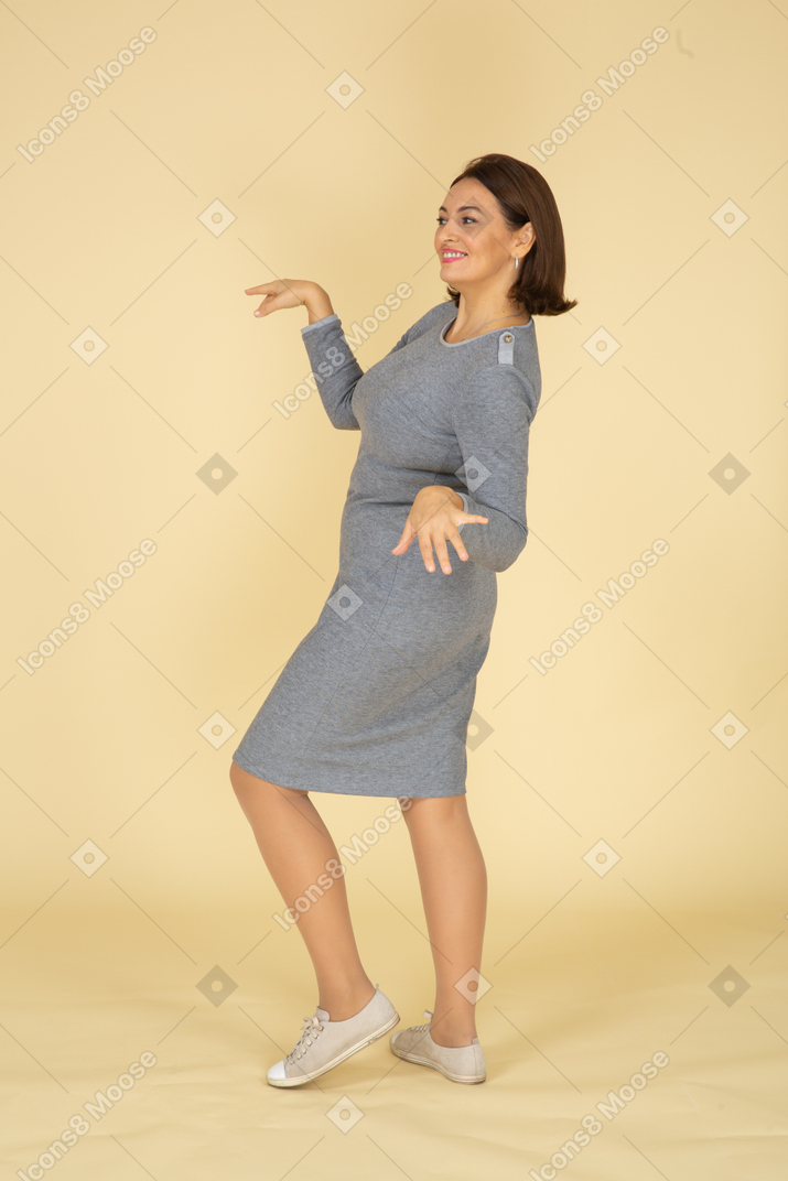 Vista lateral de uma mulher de vestido cinza dançando