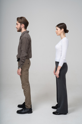 Side view of a young couple in office clothing standing still