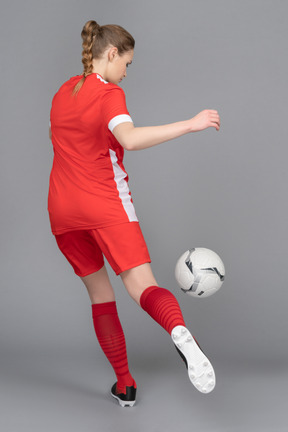 A sporty female player is about to kick the ball