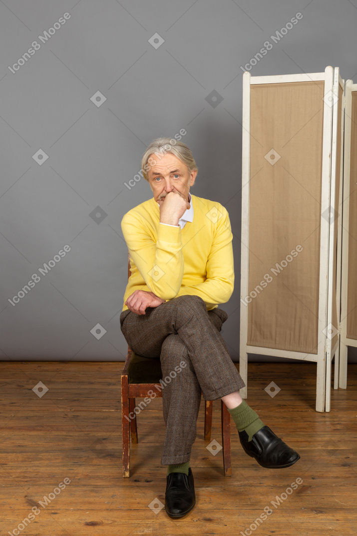 Man sitting cross-legged with his hand on his chin