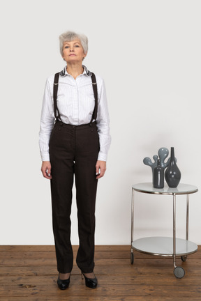 Vista frontal de una anciana en ropa de oficina de pie todavía en la habitación