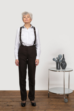 Front view of an old female in office clothes standing still in the room