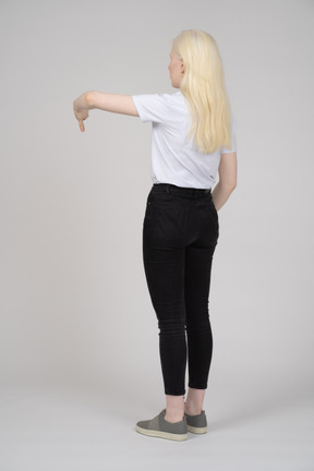Вид сзади на молодую блондинку с опущенными большими пальцами