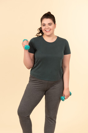 Young plus size woman in sport clothes doing physical exercises