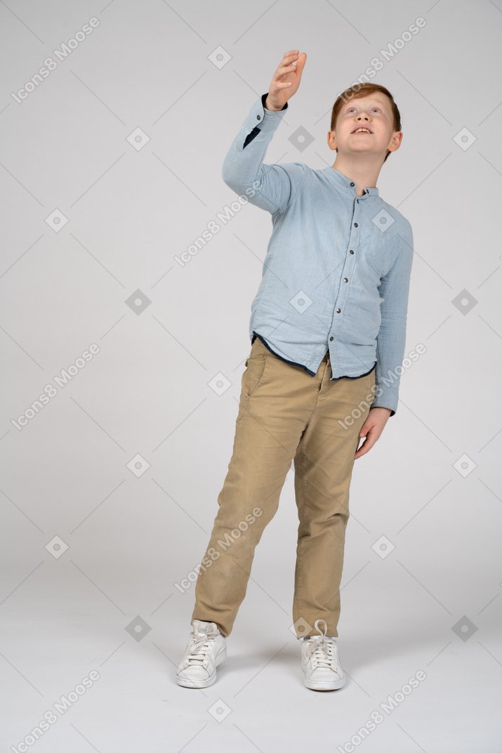 Front view of cute boy pointing up with a hand