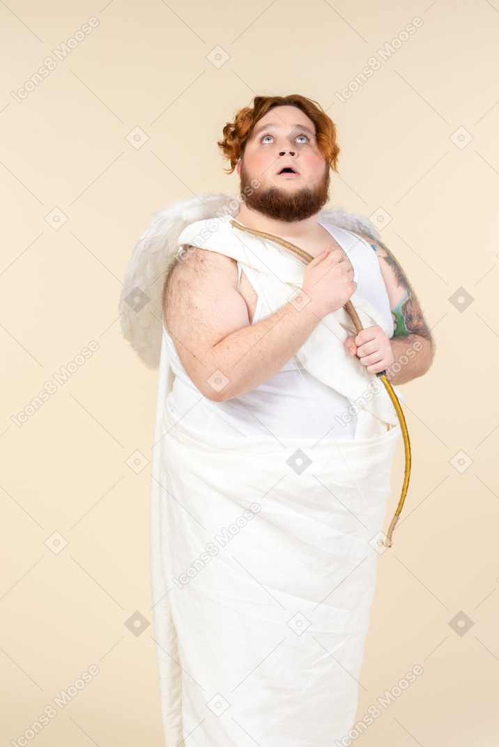 Big guy dressed as a cupid holding bow and looking up