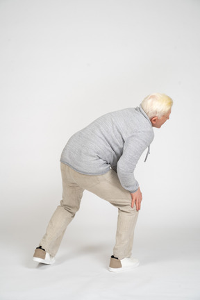 Back view of man standing with his hands on his knee