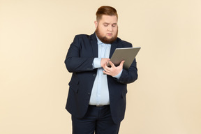 Задумчивый молодой избыточный вес офисный работник, проведение цифровой планшет