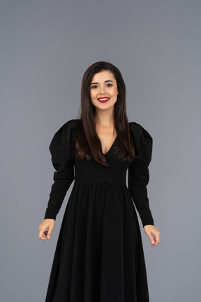 Front view of a smiling young lady in a black dress standing still