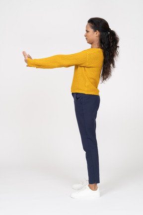 Vista lateral de uma garota com roupas casuais em pé com os braços estendidos