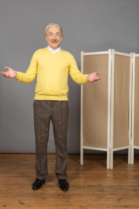 Front view of a smiling old man near the screen raising hands