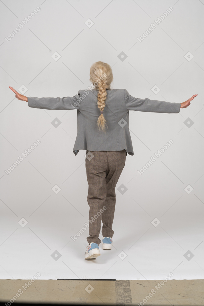 Back view of an old lady in suit outspreading arms
