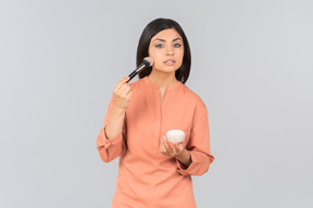 Indian woman applying face powder on her face