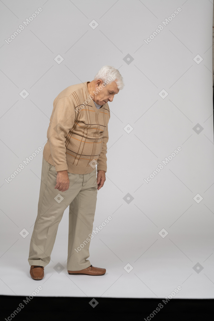 Старик в повседневной одежде смотрит вниз