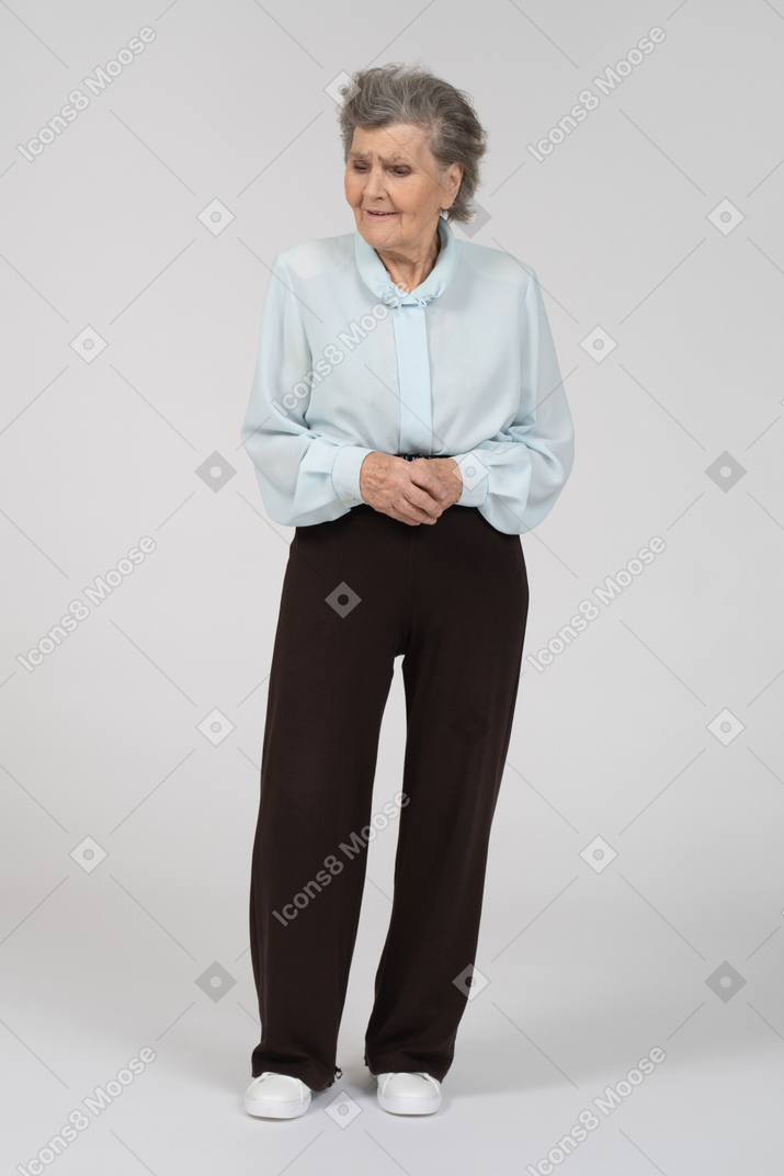 Front view of an old woman looking concerned with clasped hands