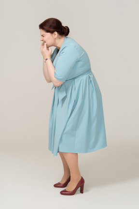 Vista lateral de uma mulher de vestido azul assobiando
