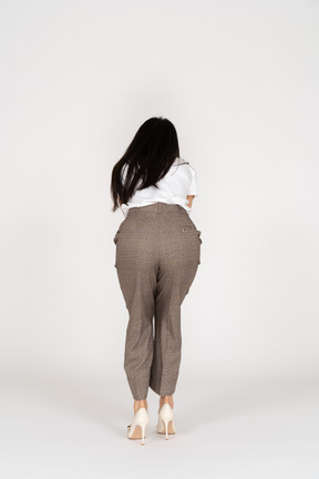 Back view of a young lady in breeches and t-shirt outstretching her hand and bending down