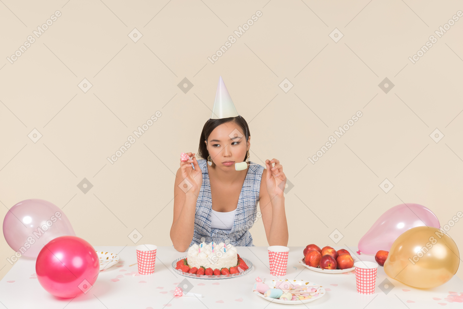 Young asian woman sitting at the birthday table and eating a cake