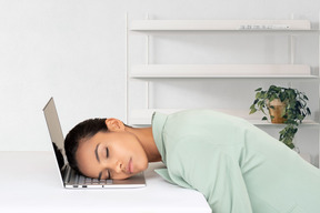 A woman laying her head on a laptop