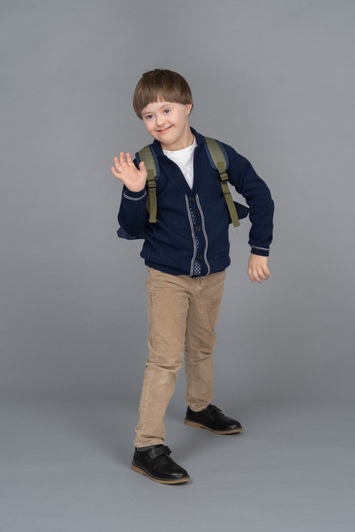 Full length portrait of a schoolboy waving
