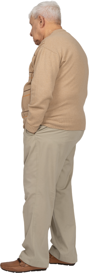 Vista lateral de un anciano con ropa informal de pie con las manos en los bolsillos