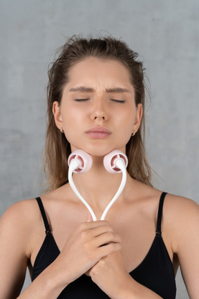 Primo piano di una giovane donna che sembra a disagio durante l'utilizzo del massaggiatore viso