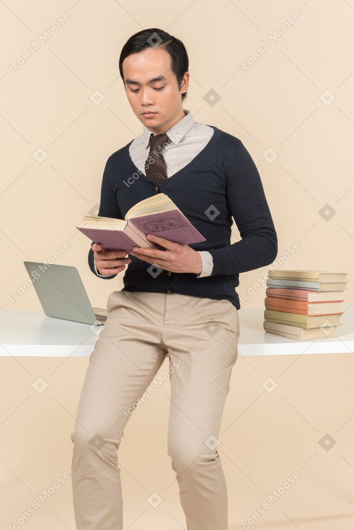 Jovem estudante asiática em uma camisola lendo um livro