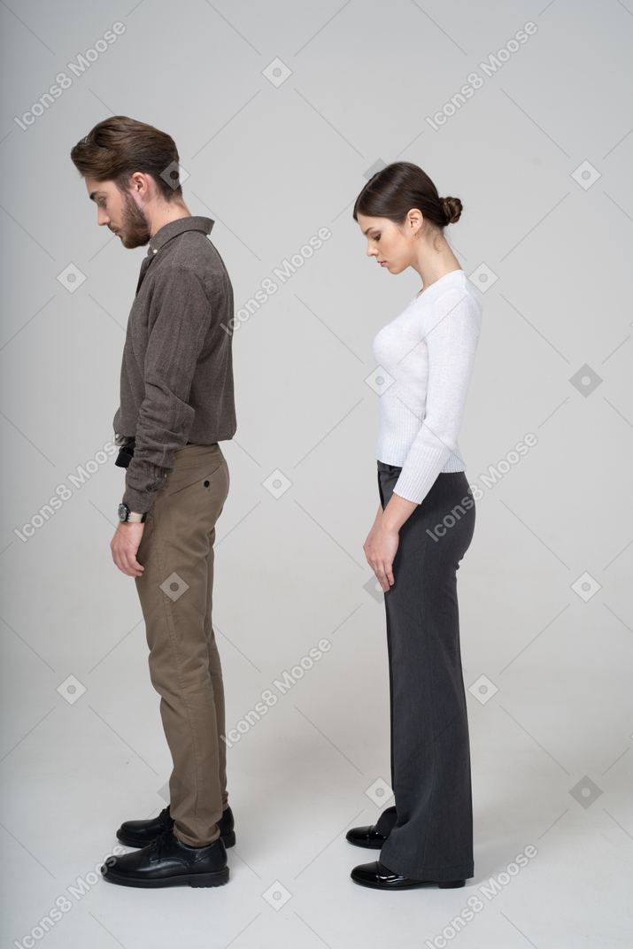 Vista laterale di una giovane coppia in abiti da ufficio guardando verso il basso