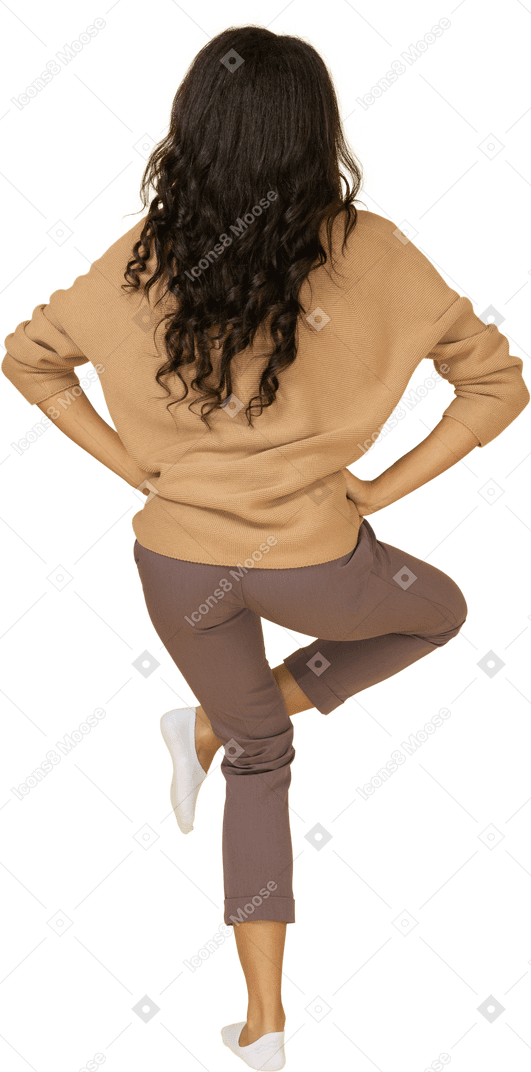 皮肤黝黑的年轻女性，抬高腿＆手放在臀部的后视图