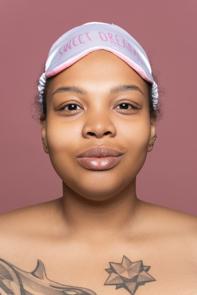 Delighted afro woman in sleeping mask facing camera