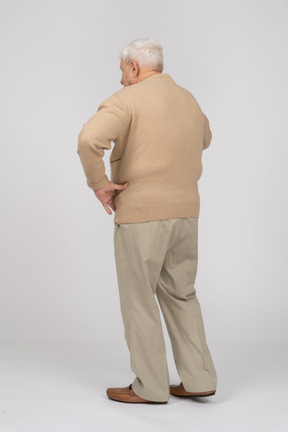 Vista posteriore di un vecchio in abiti casual in piedi con la mano sull'anca