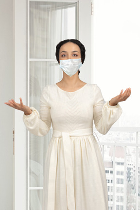 A woman in a white dress wearing a face mask