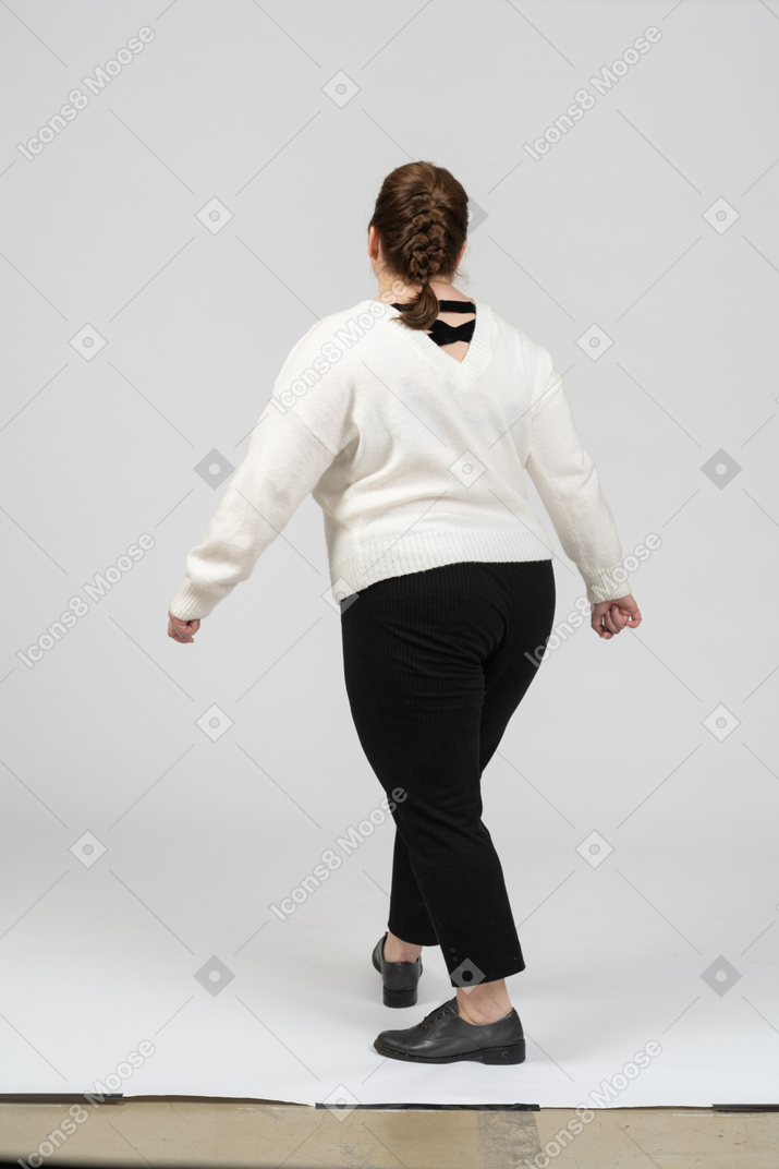 Rear view of a plump woman in casual clothes walking