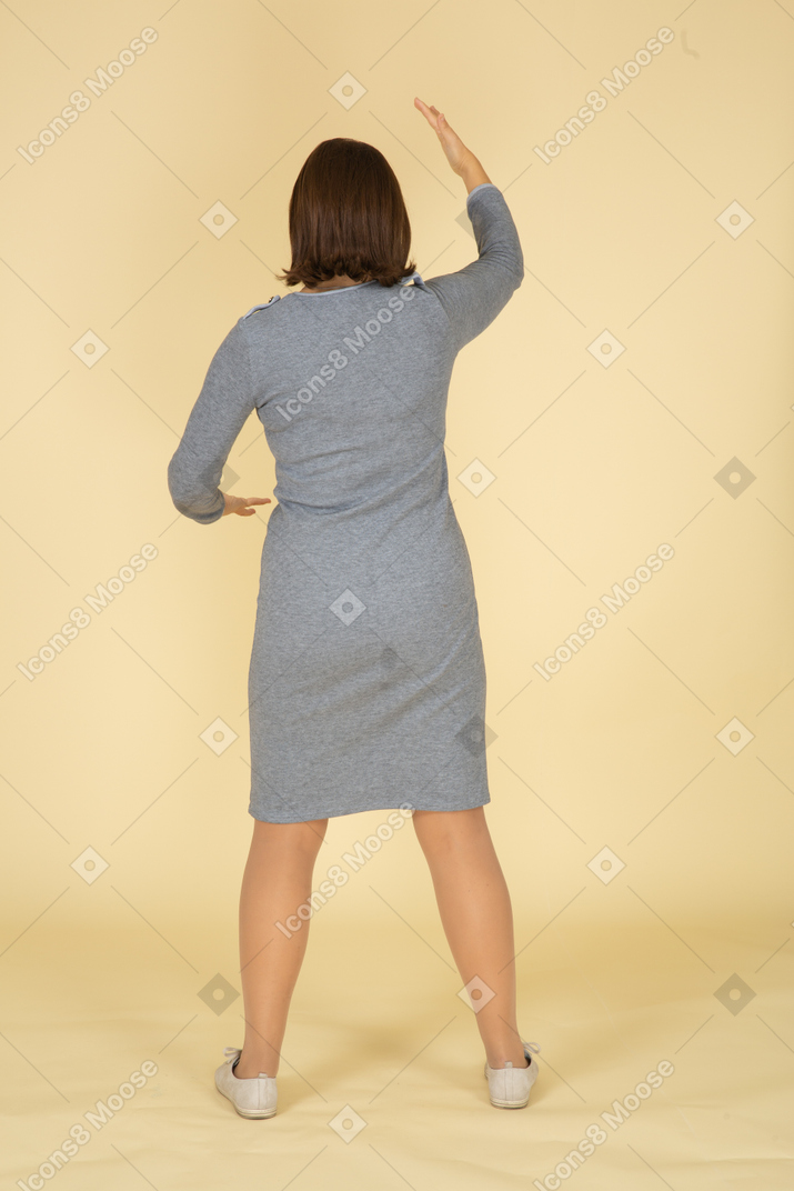 身振りで示す灰色のドレスを着た女性の背面図