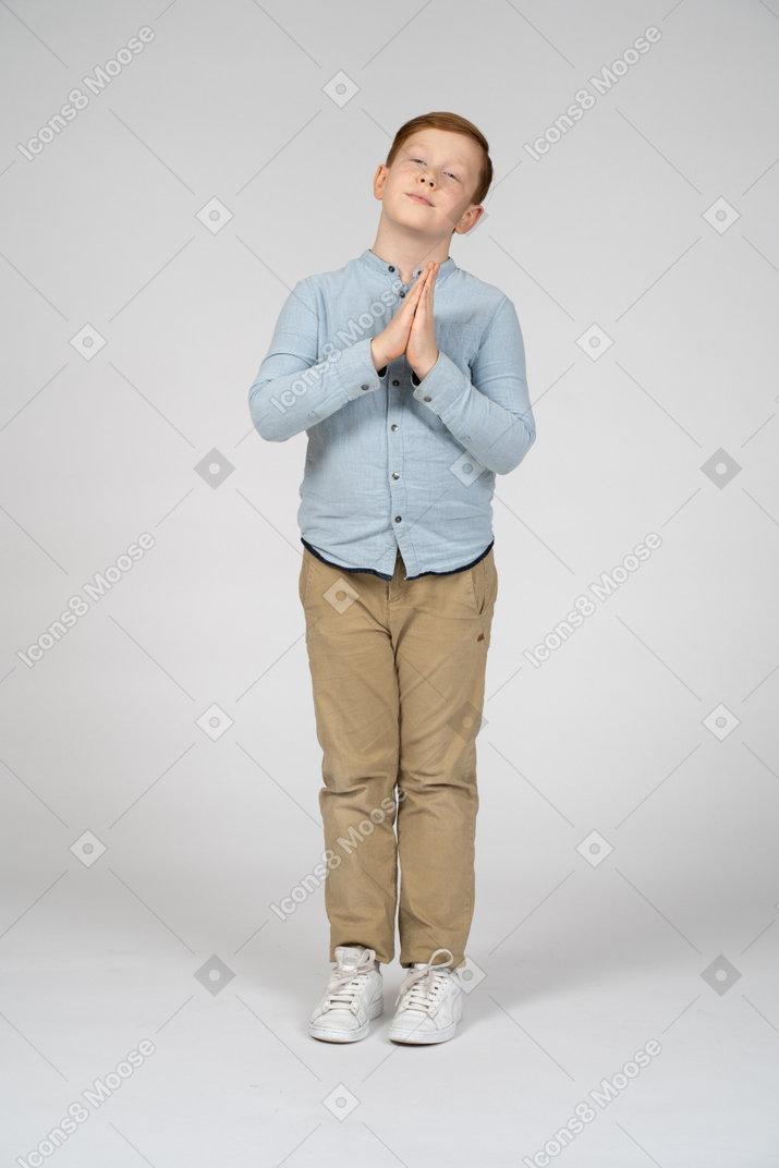 기도하는 몸짓을 하는 귀여운 소년의 전면 모습