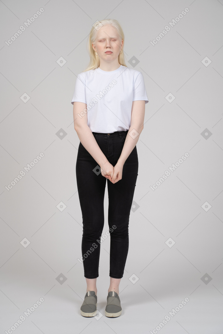 Front view of a young woman in casual clothes standing with eyes closed