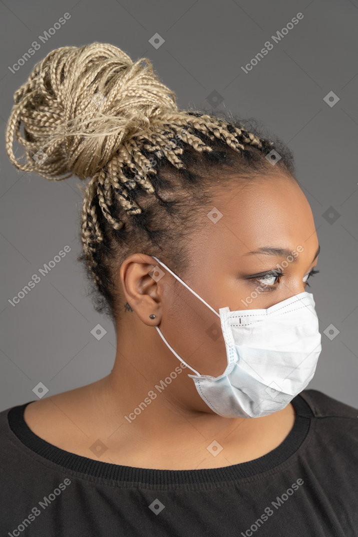 Mulher afro-americana com máscara médica olhando para o lado