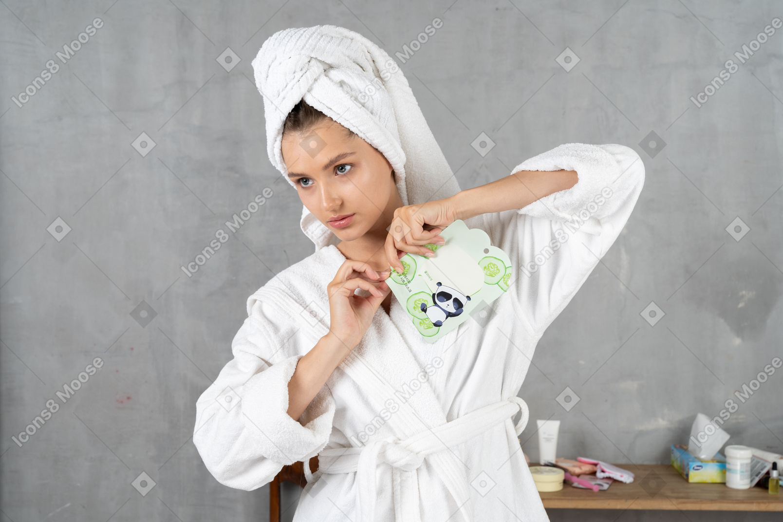Woman in bathrobe tearing open a sheet mask pack
