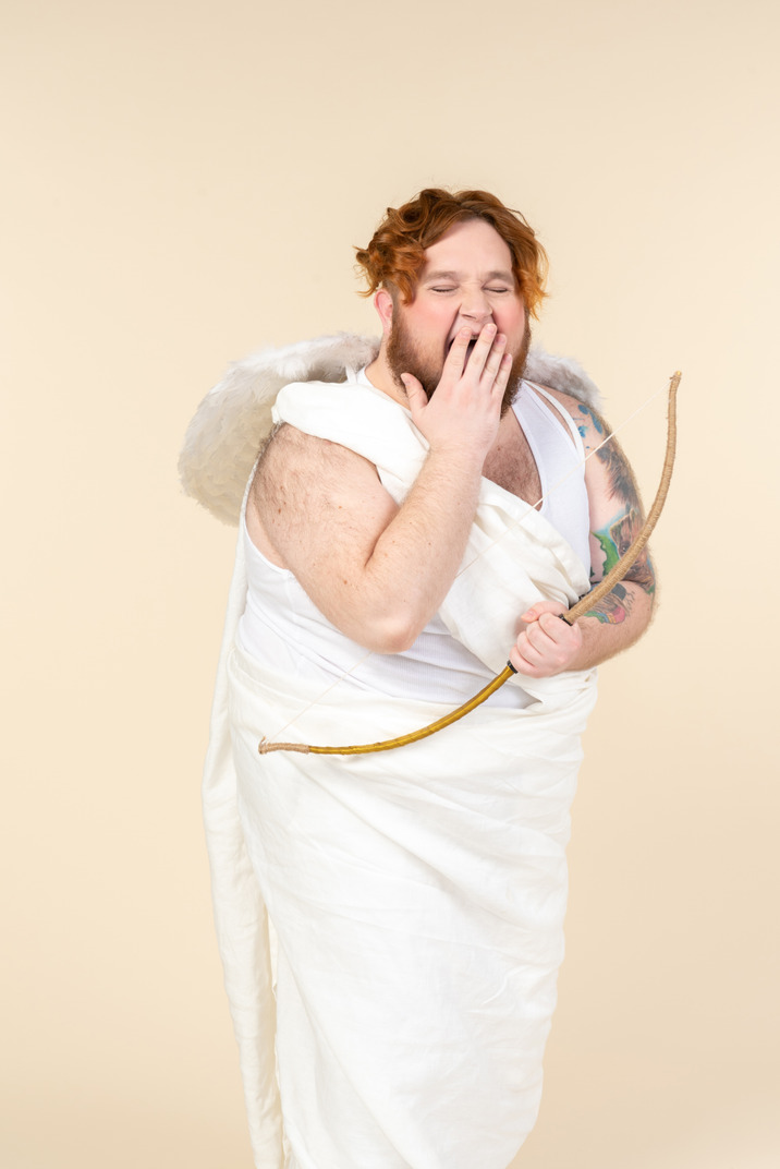 Big guy dressed as a cupid holding bow and arrow and yawning