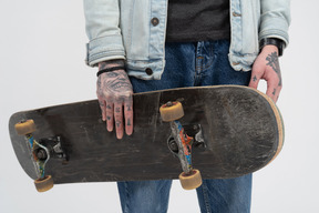 Skateboard in tattooed hands