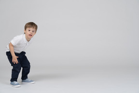 Surprised little boy standing with bent knees