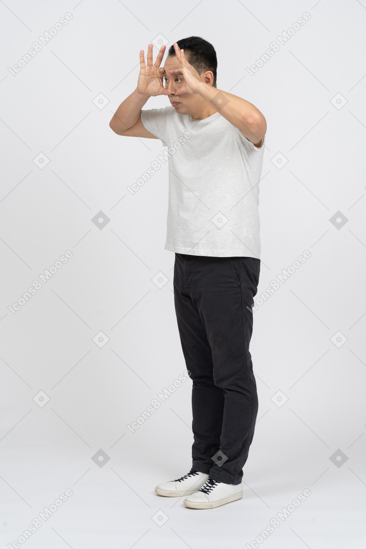 Hombre con ropa informal mirando a través de los dedos