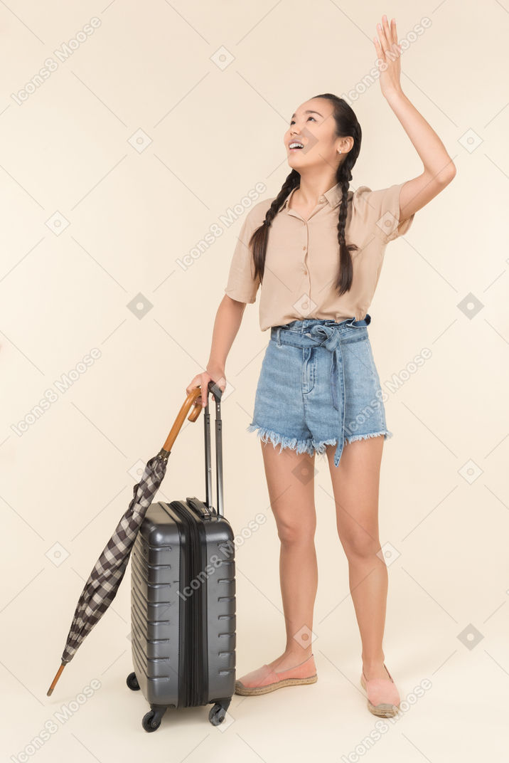 Young woman with umbrella and suitcase dissatisfied with the rain