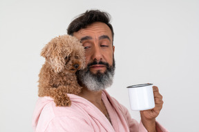 Hombre tomando un café de la mañana y un cachorro sentado en su hombro