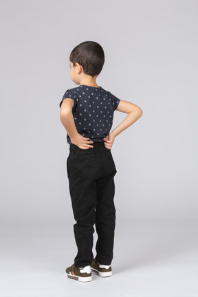 Vista posteriore di un ragazzo carino in abiti casual in posa con le mani sulla schiena