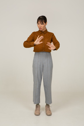 Vista frontal de una joven mujer asiática en calzones y blusa extendiendo sus brazos