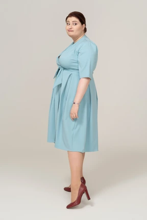 Side view of a woman in blue dress looking at camera andmaking faces