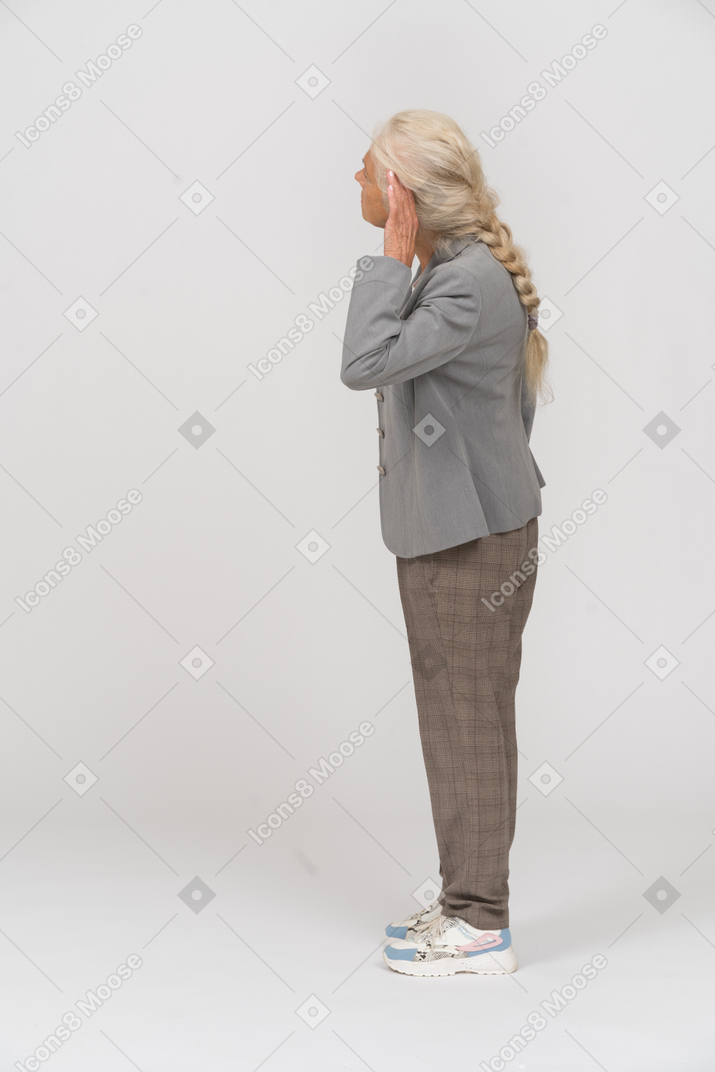 Vista lateral de una anciana en traje escuchando atentamente