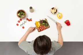 A young woman holding a cutting board with vegetables